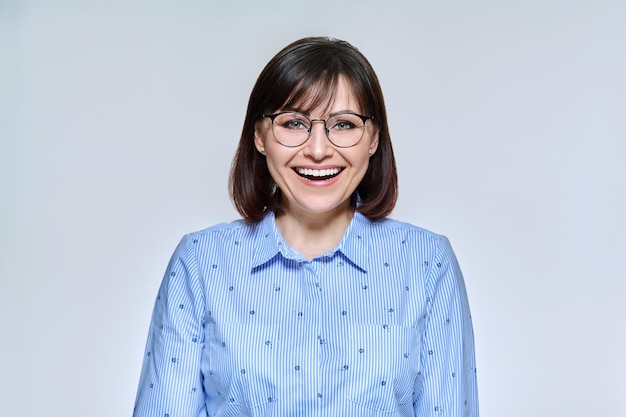 Retrato de mujer madura de negocios positiva confiada mirando a la cámara sobre fondo de estudio claro