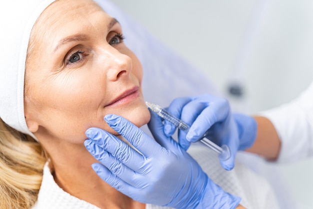 Retrato de una mujer madura soñadora recibiendo una inyección de belleza en su labio inferior de cerca