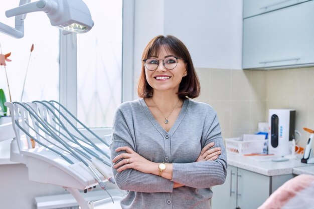 Retrato de mujer madura sonriente en clínica dental mirando a la cámara