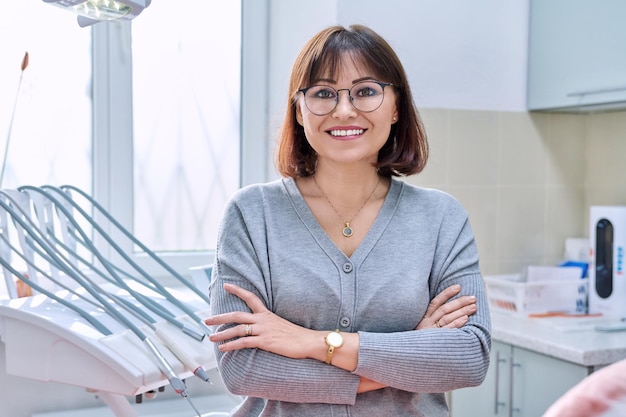 Retrato de mujer madura sonriente en clínica dental mirando a la cámara