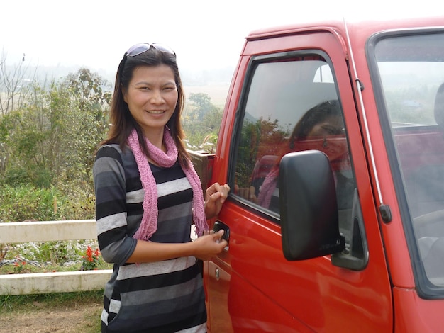 Foto retrato de una mujer madura sonriente de pie junto a una camioneta