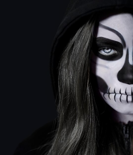 Retrato de una mujer con maquillaje de cráneo sobre fondo negro Halloween
