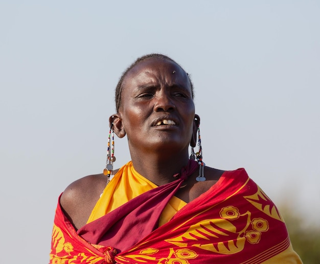 Un retrato de una mujer Masai Mara con ropa tradicional cantando una canción. Masai Mara, Kenia