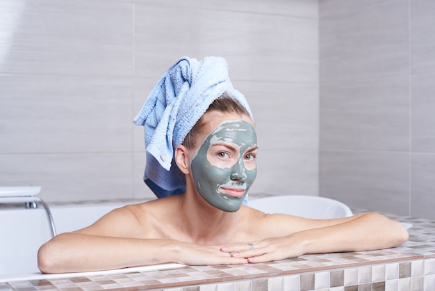 Retrato de una mujer con máscara de alginato facial tumbado en el baño retro en el baño.