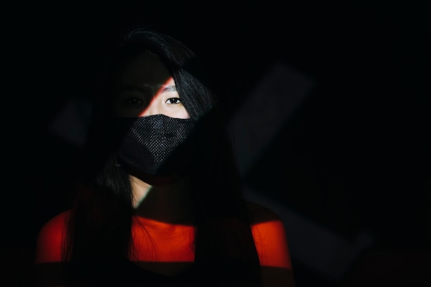 Retrato de una mujer con máscara en el cuarto oscuro