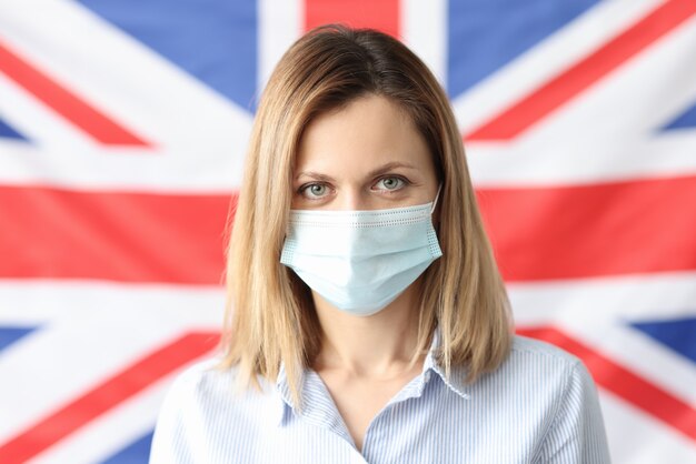 Retrato de mujer con máscara protectora contra el fondo de la bandera británica. Cepa británica de