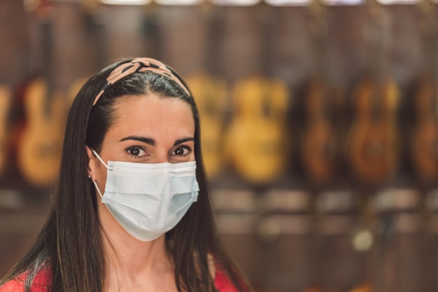 Retrato de una mujer con una máscara en una tienda de instrumentos llena de guitarras