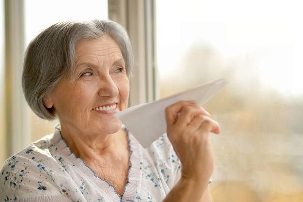 Retrato de mujer mayor con avión de papel