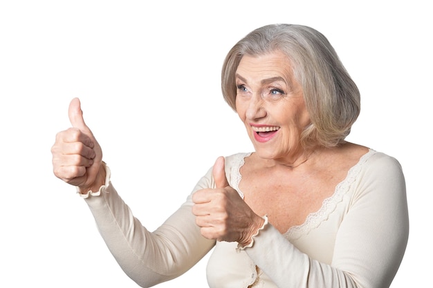 Retrato de una mujer mayor feliz con una blusa blanca mostrando los pulgares hacia arriba