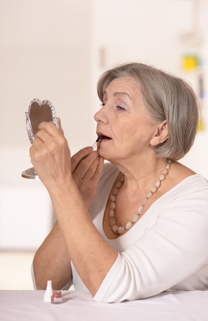 Retrato de una mujer mayor feliz en casa mirando en el espejo