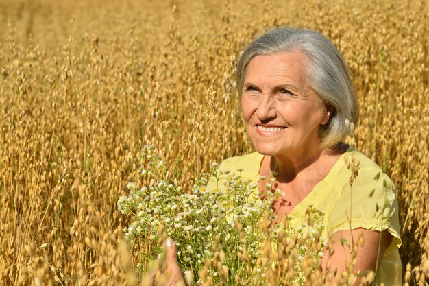 Retrato de una mujer mayor con flores en el campo