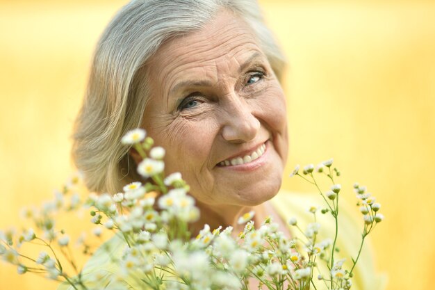 Retrato de una mujer mayor con flores en el campo