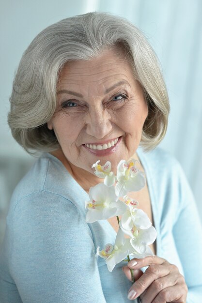 Retrato de mujer mayor con flores de orquídeas en flor