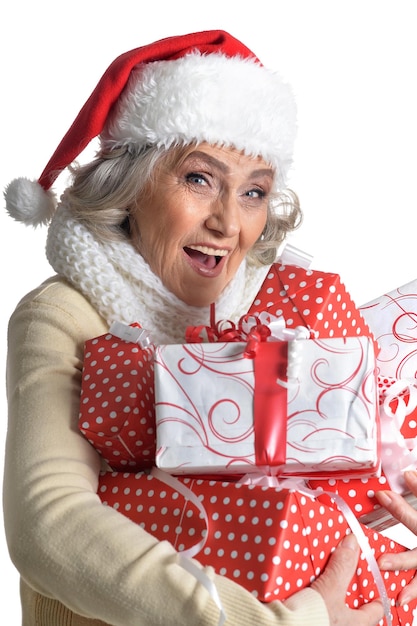 Retrato de mujer mayor con gorro de Papá Noel con regalos aislado sobre fondo blanco.