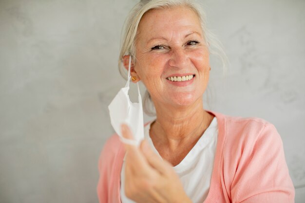 Foto retrato de mujer mayor quitándose la mascarilla facial médica protectora para protegerse del virus