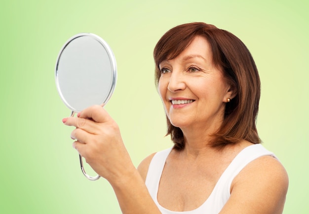 retrato de una mujer mayor sonriente con un espejo