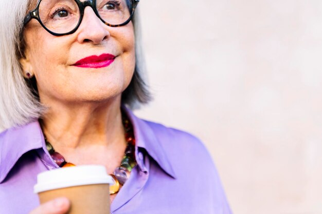 Retrato de una mujer mayor sonriente sosteniendo un café