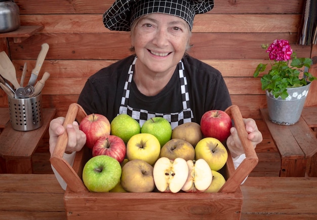 Foto retrato de una mujer mayor sonriente sosteniendo un contenedor con frutas en la cocina