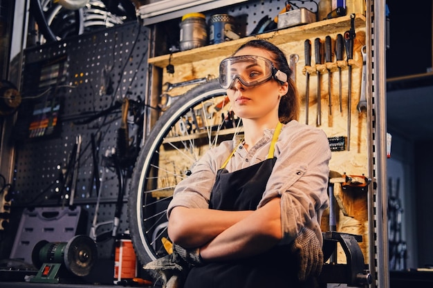 Retrato de mujer mecánica de bicicletas sobre fondo de soporte de herramientas en un taller.