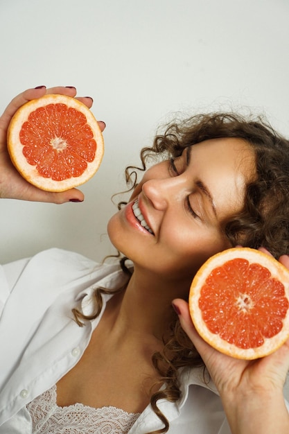 Retrato de mujer de mediana edad bonita con pelo rizado con pomelo en casa - sala de luz. Felicidad, belleza y salud - foto vertical