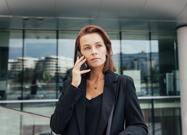 Retrato de una mujer de mediana edad con cabello rojo haciendo una llamada telefónica