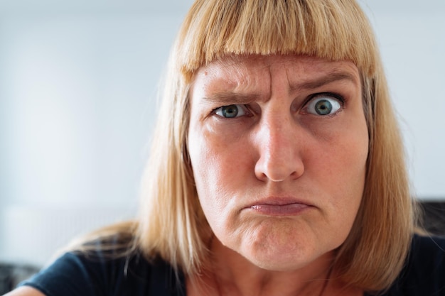 Retrato mujer de mediana edad rubia haciendo muecas en el espejo delantero