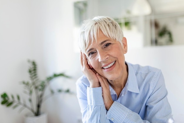 Retrato de mujer de mediana edad sonriente mirando a cámara. Hermosa anciana sonriendo en casa.