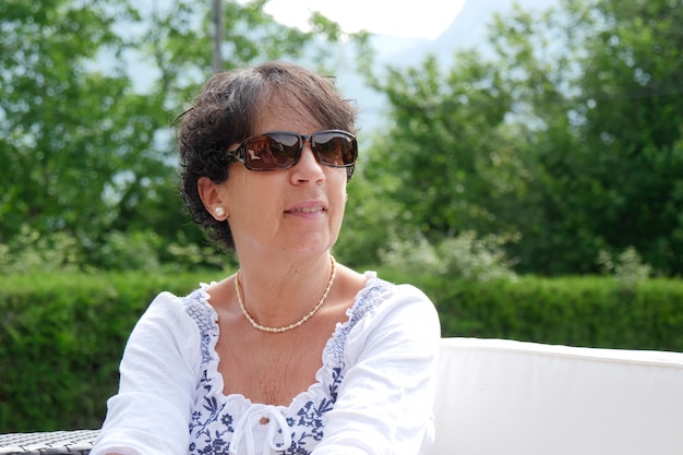 Retrato de mujer de mediana edad sonriente sentada en el jardín en casa