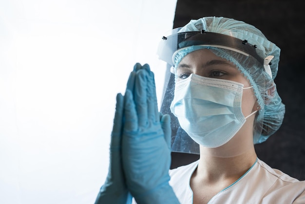 Retrato de una mujer médica en uniforme con los ojos cerrados, las manos juntas y orando a Dios Concepto de fe y esperanza