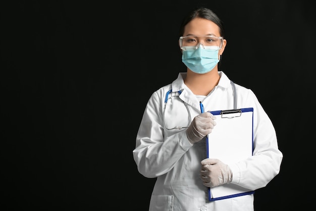 Retrato de mujer médico asiático con portapapeles sobre superficie oscura