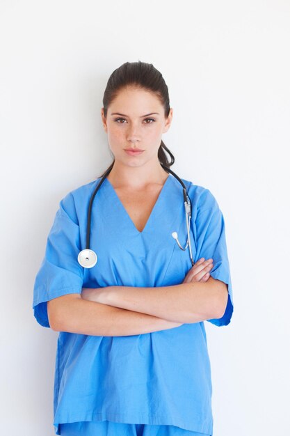 Foto retrato de mujer y médico con los brazos cruzados de pie aislado contra un fondo blanco de estudio experta profesional médica o enfermera segura de sí misma con estetoscopio para atención médica o perfil