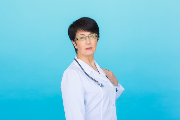 Retrato de mujer médico con estetoscopio sobre fondo azul.