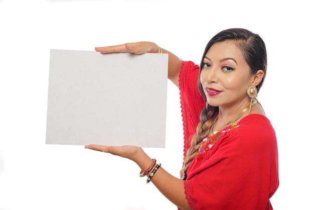 Retrato de mujer mexicana en traje tradicional sosteniendo un cartel en blanco. Fondo blanco.