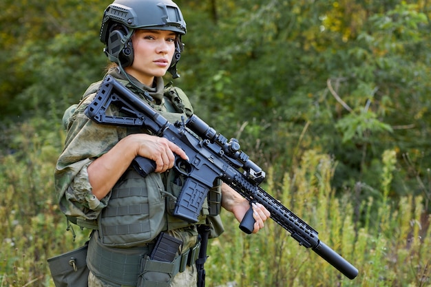 Retrato de mujer militar segura con una pistola en el bosque