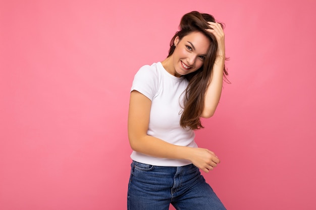 Retrato de mujer de moda alegre positiva en camiseta blanca casual para maqueta aislado sobre fondo rosa con espacio de copia.