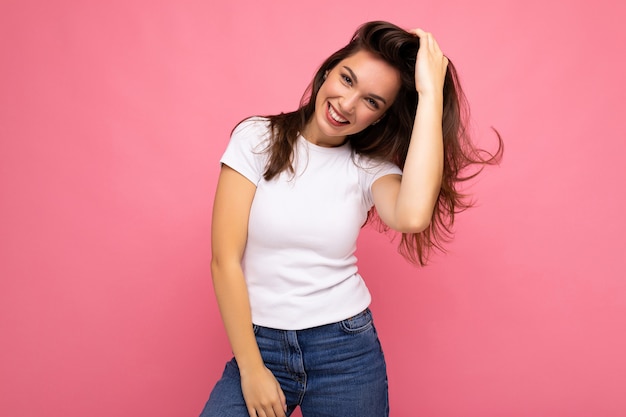 Foto retrato de mujer de moda alegre positiva en camiseta casual para maqueta aislado sobre fondo rosa con espacio de copia.