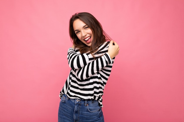 Retrato de mujer de moda alegre positiva en ropa casual aislado sobre fondo rosa con espacio de copia.