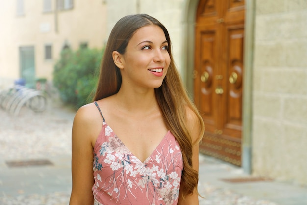 Retrato de mujer de moda hermosa caminando mira hacia el lado en la calle del casco antiguo de Italia.