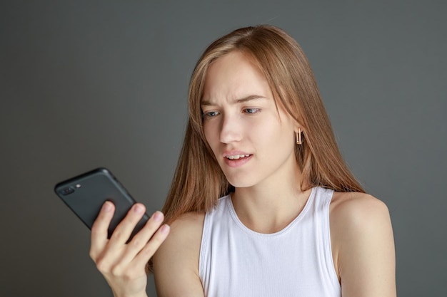 Retrato de una mujer morena de 20 años usando un teléfono celular mientras estaba aislada sobre un fondo amarillo