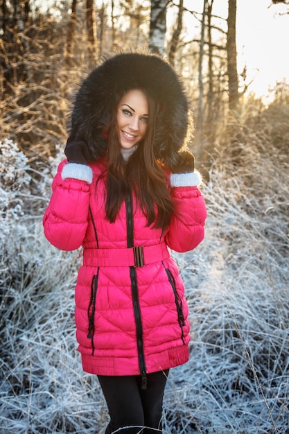 Retrato de mujer morena en abrigo de invierno rosa.