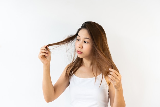Retrato de mujer morena asiática joven frustrada con el pelo desordenado en la superficie blanca. De cerca.