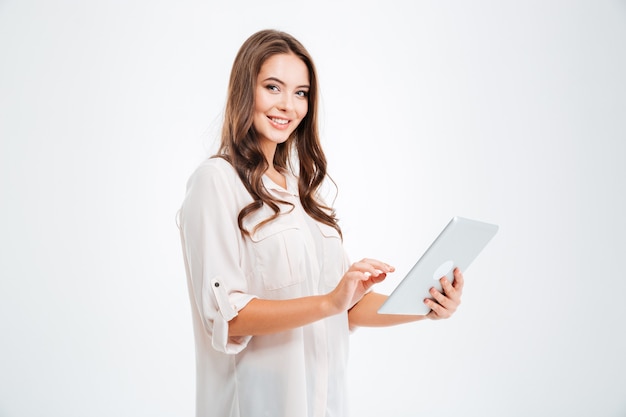 Retrato de una mujer morena feliz con tablet PC aislado en una pared blanca