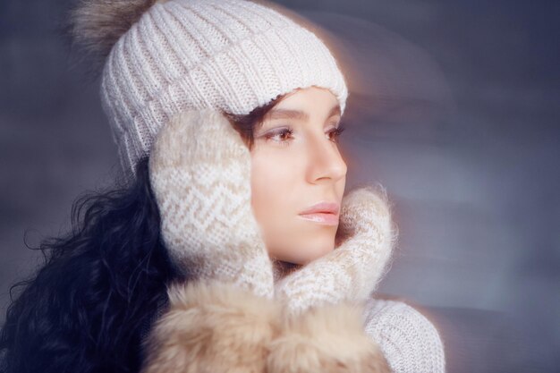 Retrato de mujer morena con gorro de invierno cálido y guantes de piel.