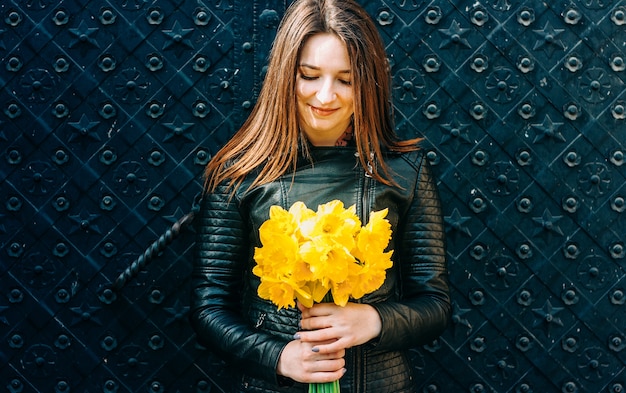 Retrato de una mujer morena joven que sostiene las flores amarillas de la primavera