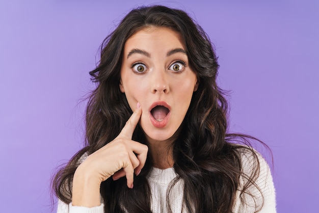 Retrato de mujer morena joven sorprendida posando aislado en la pared púrpura