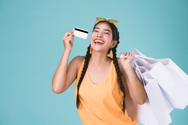 Retrato de mujer morena joven con tarjeta de crédito y bolsas de compras