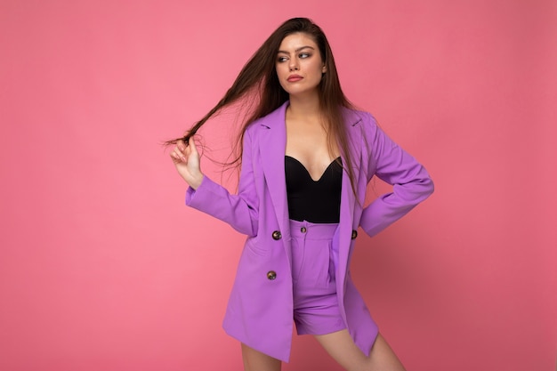 Retrato de mujer morena de moda atractiva fresca sexy joven con elegante traje violeta aislado sobre fondo rosa con espacio vacío. Concepto de negocio.