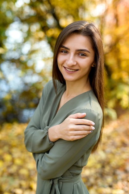 Retrato de mujer morena en otoño parque con vestido verde oliva