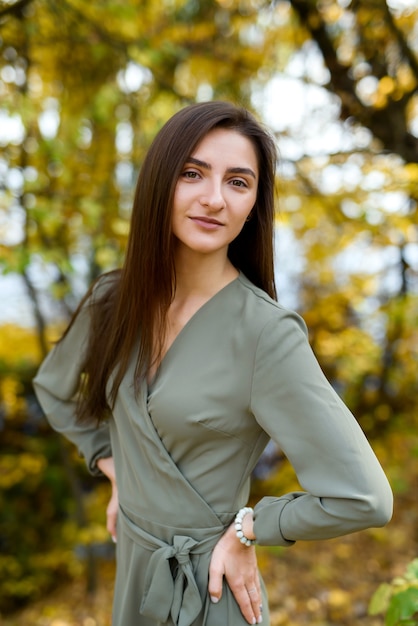 Retrato de mujer morena en otoño parque con vestido verde oliva