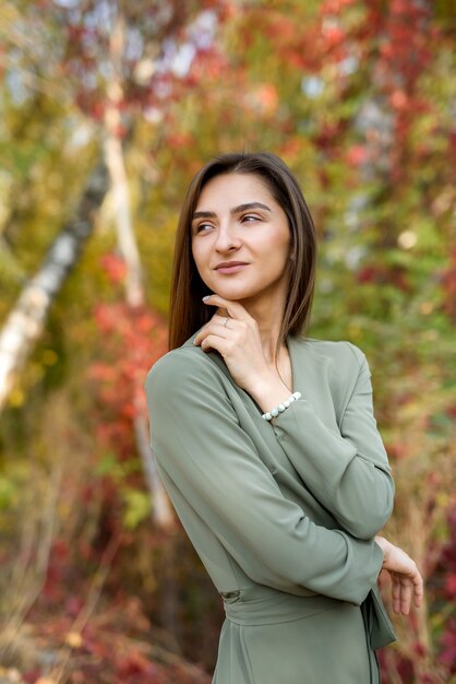 Retrato de mujer morena en otoño parque con vestido verde oliva